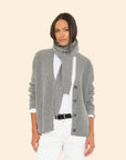 A woman wearing an ultra-soft cardigan and the Le Petit Scarf over a white shirt and pants, posing against a plain light background.