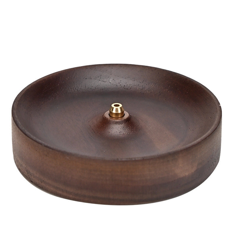 The Faire Walnut Wood Incense Burner features a round, shallow design with a central brass fitting for incense sticks. Its smooth, polished finish is inspired by traditional Chinese artistry and pairs well with handcrafted ceramics and rustic glazes.