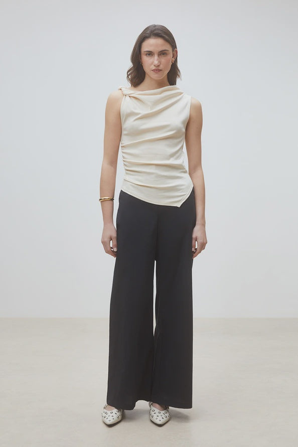 Cream draped sleeveless top and black organic cotton pants by SUNCOO, styled against a plain light background.