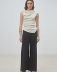 Cream draped sleeveless top and black organic cotton pants by SUNCOO, styled against a plain light background.