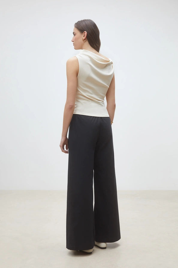 Sleeveless cream top and black wide-leg pants by SUNCOO Jet in soft organic cotton, shown from the back.