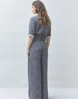 SUNCOO Jerk textured grey jumpsuit and recycled polyester pants modeled from behind, wavy hair adds casual style.