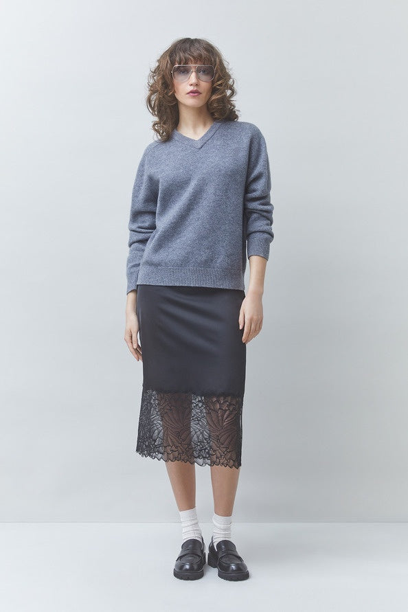 SUNCOO Face Skirt in graphic print styled with a gray sweater, showcasing modern flair against a simple backdrop.