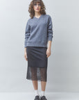 SUNCOO Face Skirt in graphic print styled with a gray sweater, showcasing modern flair against a simple backdrop.