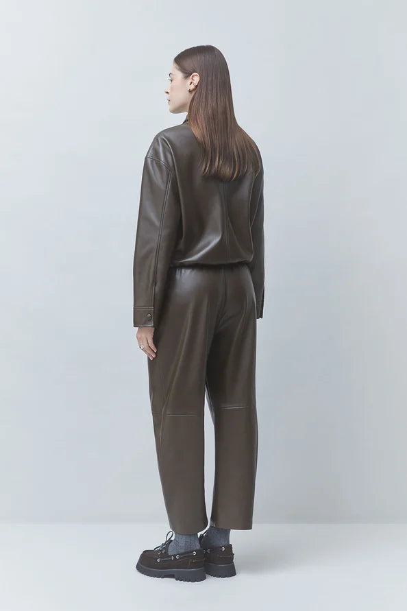 Dark brown SUNCOO LENNOX pleather jacket styled with black shoes, shown from the back against a light background.