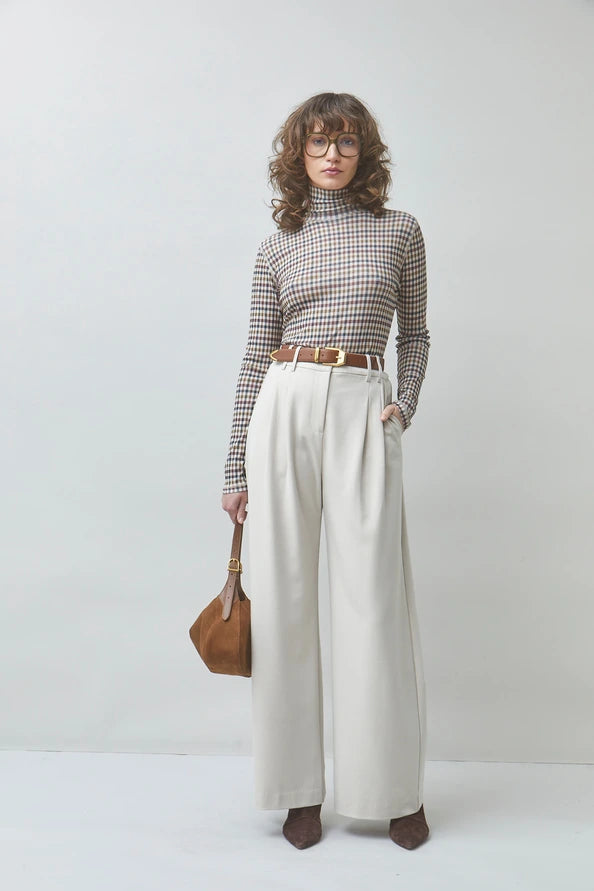 SUNCOO Manech check T-shirt paired with white pants and brown accessories styled in a minimal, modern setting.
