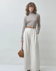 SUNCOO Manech check T-shirt paired with white pants and brown accessories styled in a minimal, modern setting.