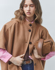 SUNCOO Ezra front-buttoned coat in soft pink, styled with a brown bag and wavy hair for a chic look.