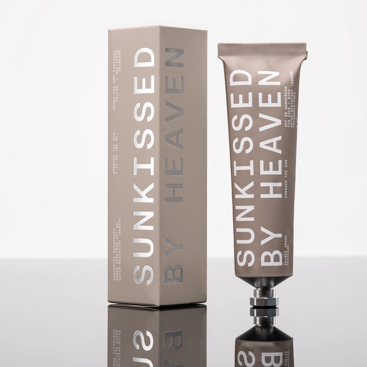 A metallic tube and matching box labeled "Tallow Sunscreen SPF 50" by Faire stand upright on a glossy surface, highlighting this sensitive skin sunscreen against a crisp white background.