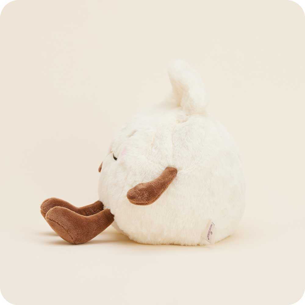 The Faire Dumpling Warmies is a round, fluffy white plush with brown arms and legs, a small tail, and embroidered face. This microwavable stuffed animal sits sideways on an off-white background and provides cozy comfort with its lavender scent.