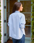 Oona Continuous Button-Up Shirt by Frank & Eileen in white, relaxed fit, modeled outdoors near glass doors.
