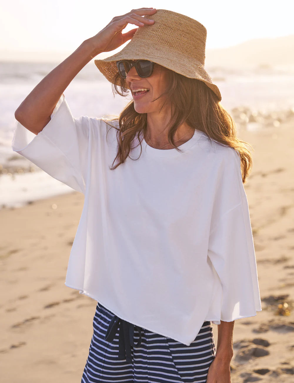 Frank & Eileen Presley Oversized Tee styled with striped pants and sunhat on a sandy beach at sunset.