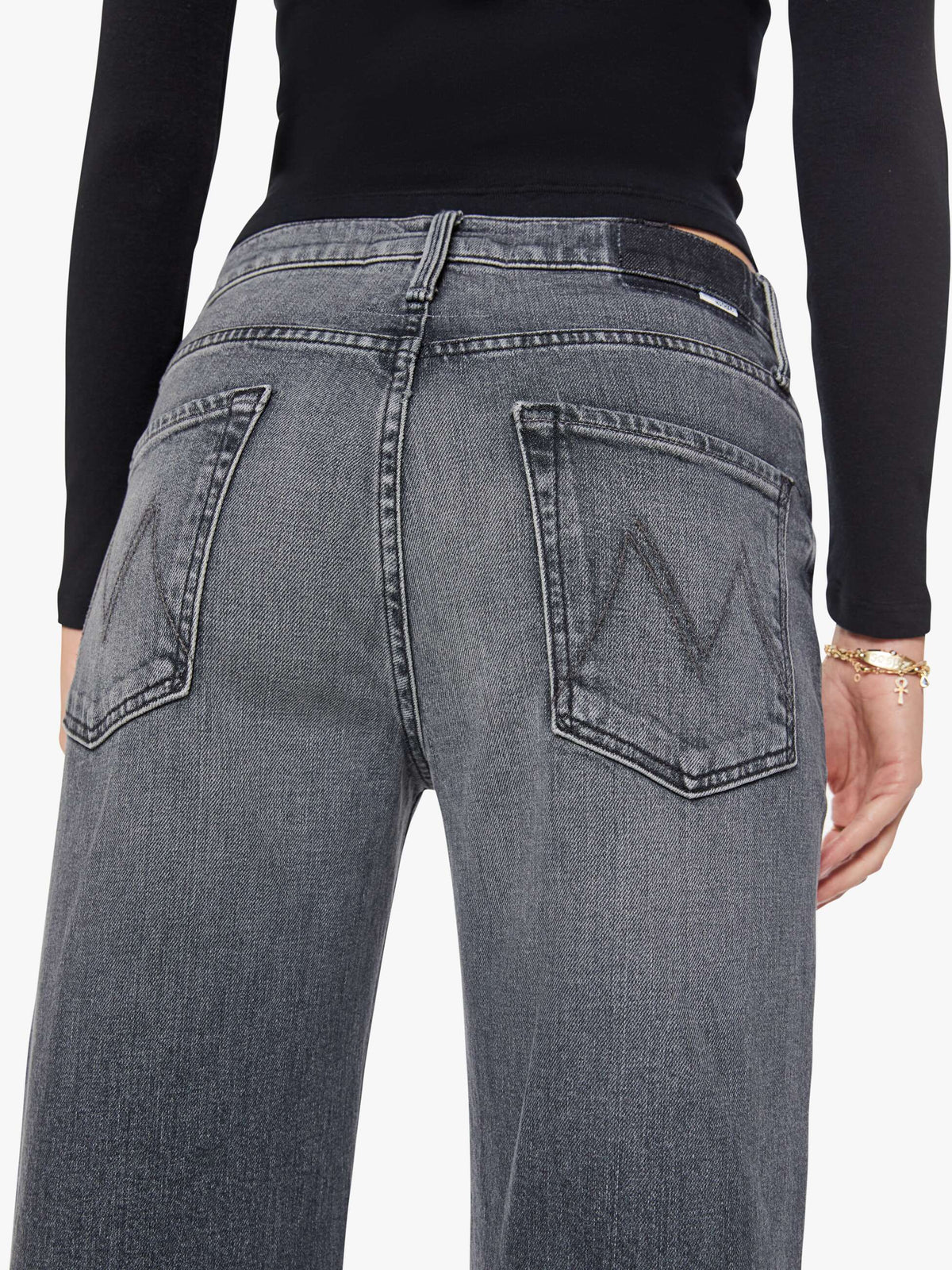 Gray slouchy jeans from Mother’s The Dodger Flood, seen from the back, paired with a black long-sleeve top.