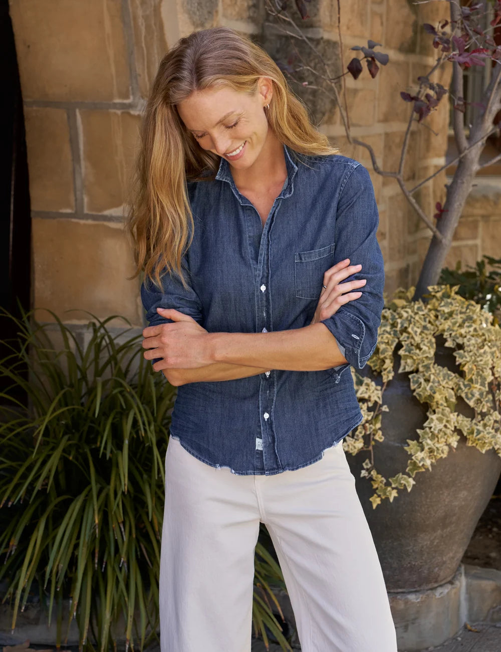 BARRY Tailored Button Up Shirt in dark blue Italian cotton denim with a raw hem worn with white pants.