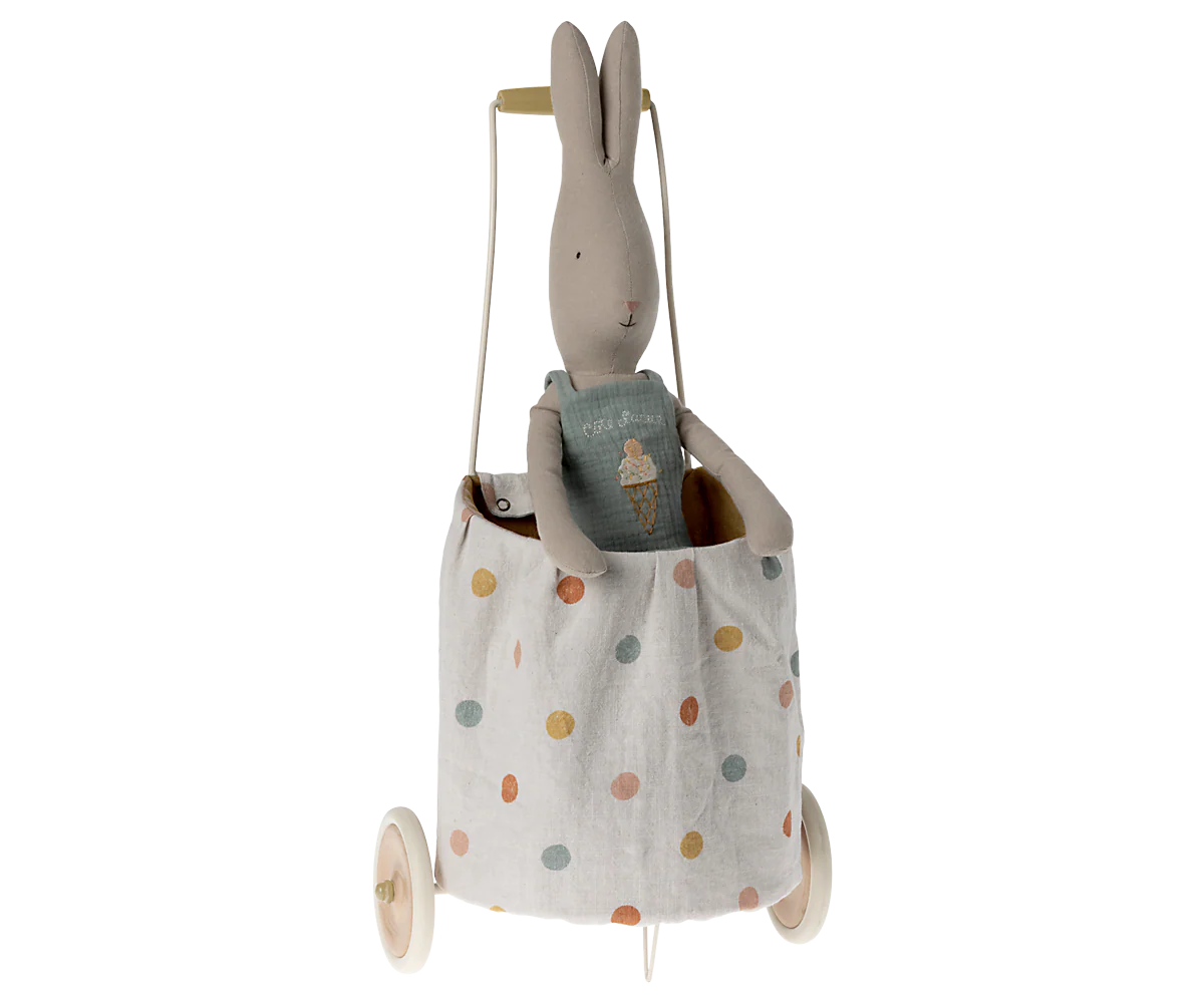 A Maileg stuffed bunny sits in the Maileg Trolley, a small linen fabric cart with colorful polka dots, white wheels, and a pull handle.