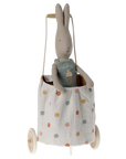 A Maileg stuffed bunny sits in the Maileg Trolley, a small linen fabric cart with colorful polka dots, white wheels, and a pull handle.