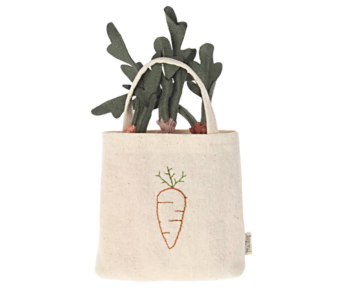 The Maileg Carrots in Bag by Maileg is a small beige tote with an embroidered carrot design and green leaves, perfect for imaginative play or as a cute decorative accent. It looks like fabric carrots are peeking out of the bag.