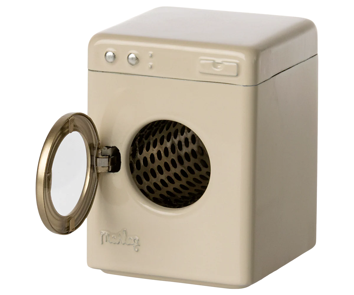 The Maileg Washing Machine by Maileg is a small, beige appliance with a round, left-opening front door that reveals a black perforated drum. It features three buttons and a rectangular panel on the top front—ideal for laundry day play.