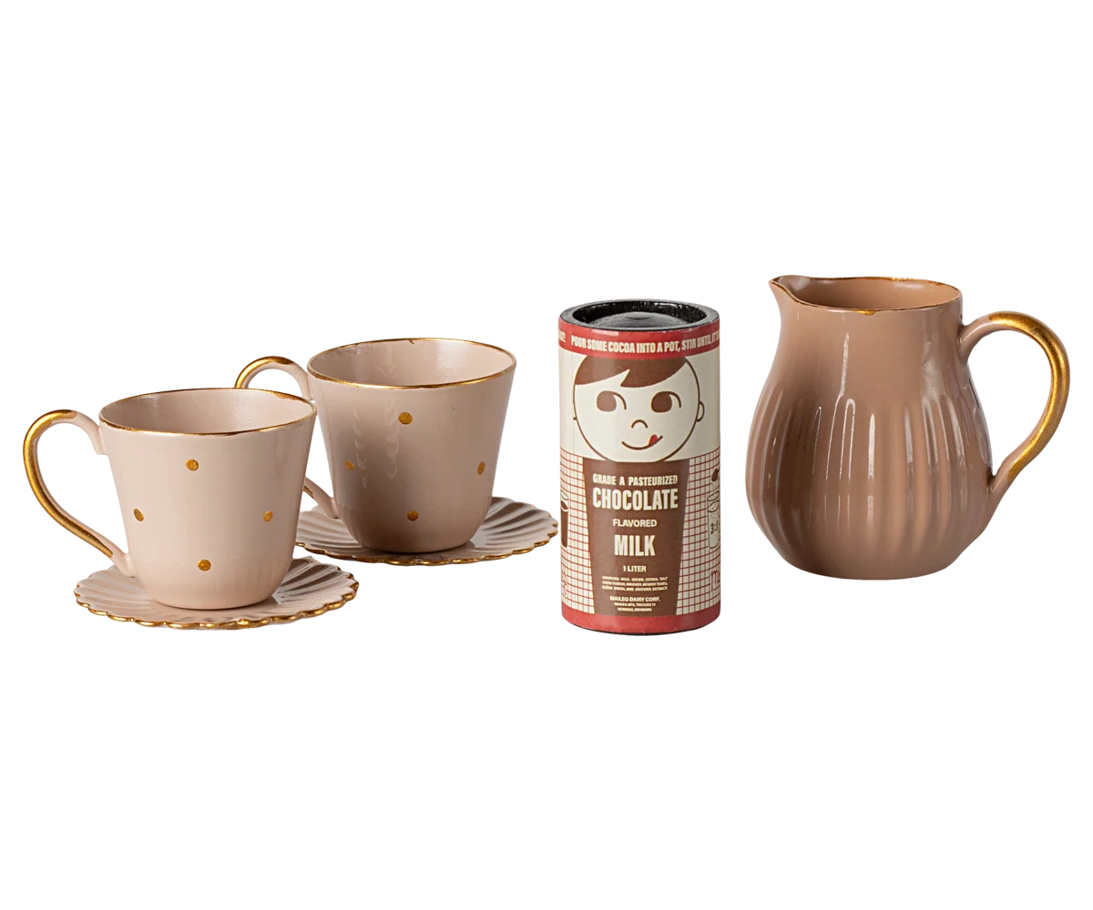 Mini hot chocolate set with two teacups, saucers, pitcher, and pretend cocoa by Maileg on white background.