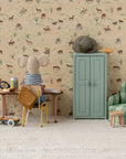 A Maileg fabric mouse doll sits at a small desk with a vintage seat and scooter nearby, facing western-themed wallpaper. To the right is a Maileg Yellow Chair, plus a blue cabinet with a hat and bread on top.