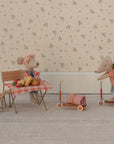Two Maileg mice in a cozy scene: one wears a headscarf at the table with food, the other in a striped shirt and backpack rides the Maileg Kick Board. Both are surrounded by charming miniature furniture and wooden details.