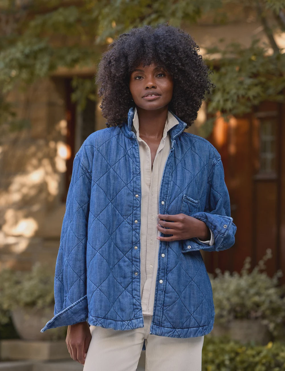 Eileen denim jacket in blue quilted diamond pattern worn over a cream button-down shirt.