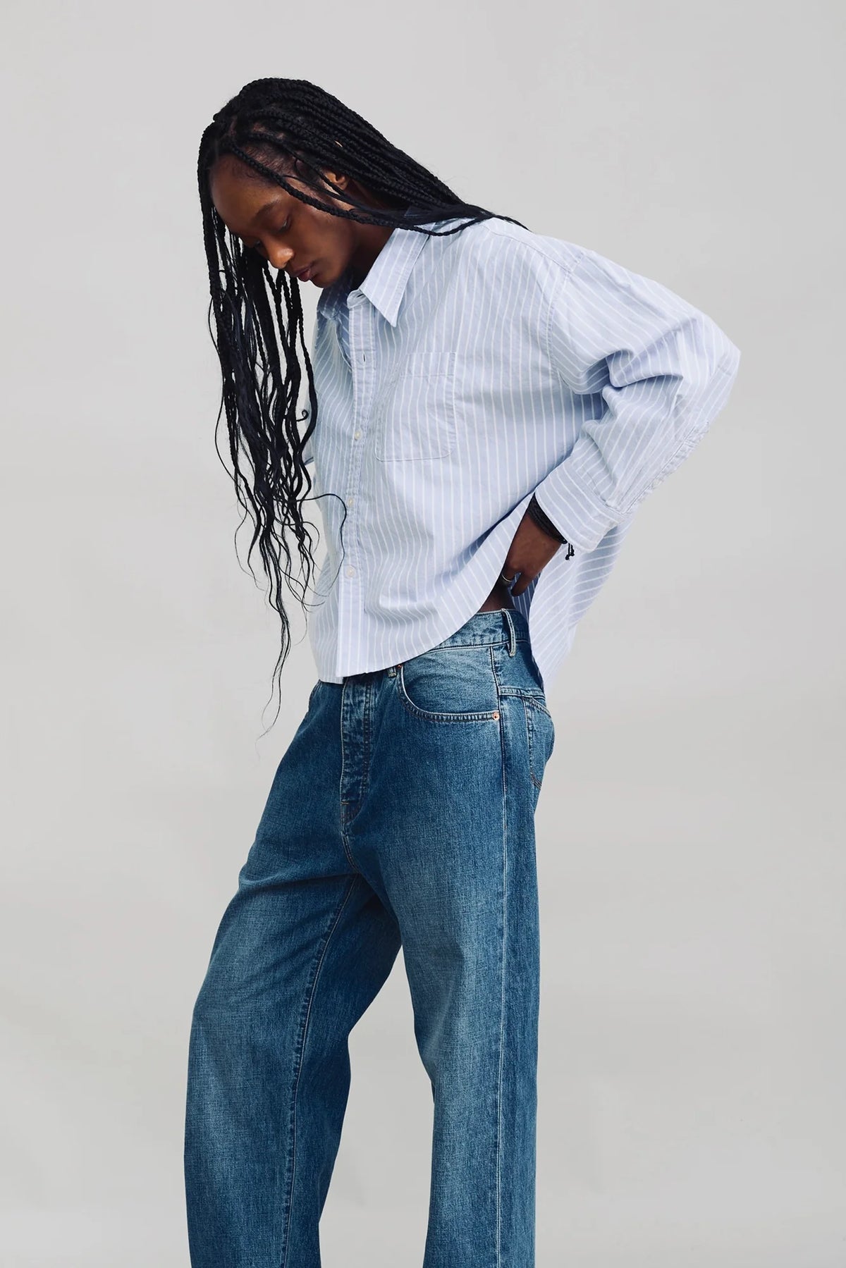 Denimist BAILEY Cropped Stripe Oxford shirt and loose jeans, styled on model with long braids against a plain backdrop.