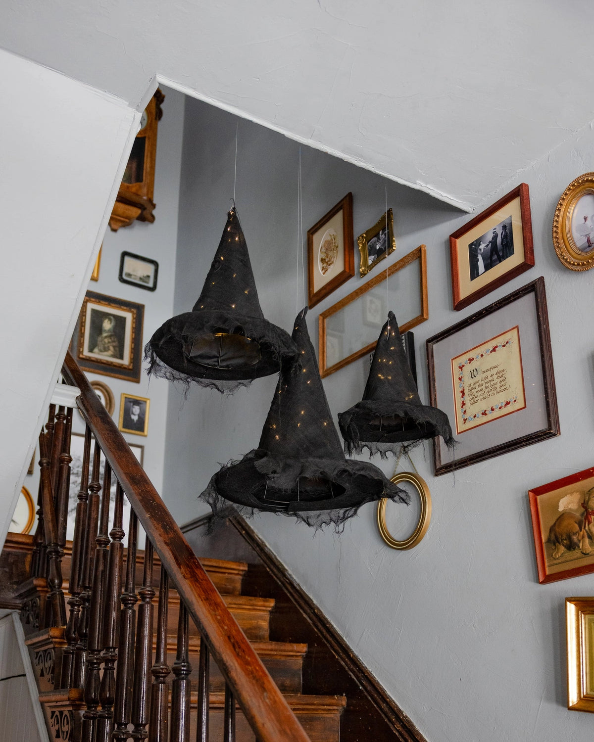 Faire light-up witch hats glowing over a staircase, creating a festive Halloween accent for Bungalow home décor.