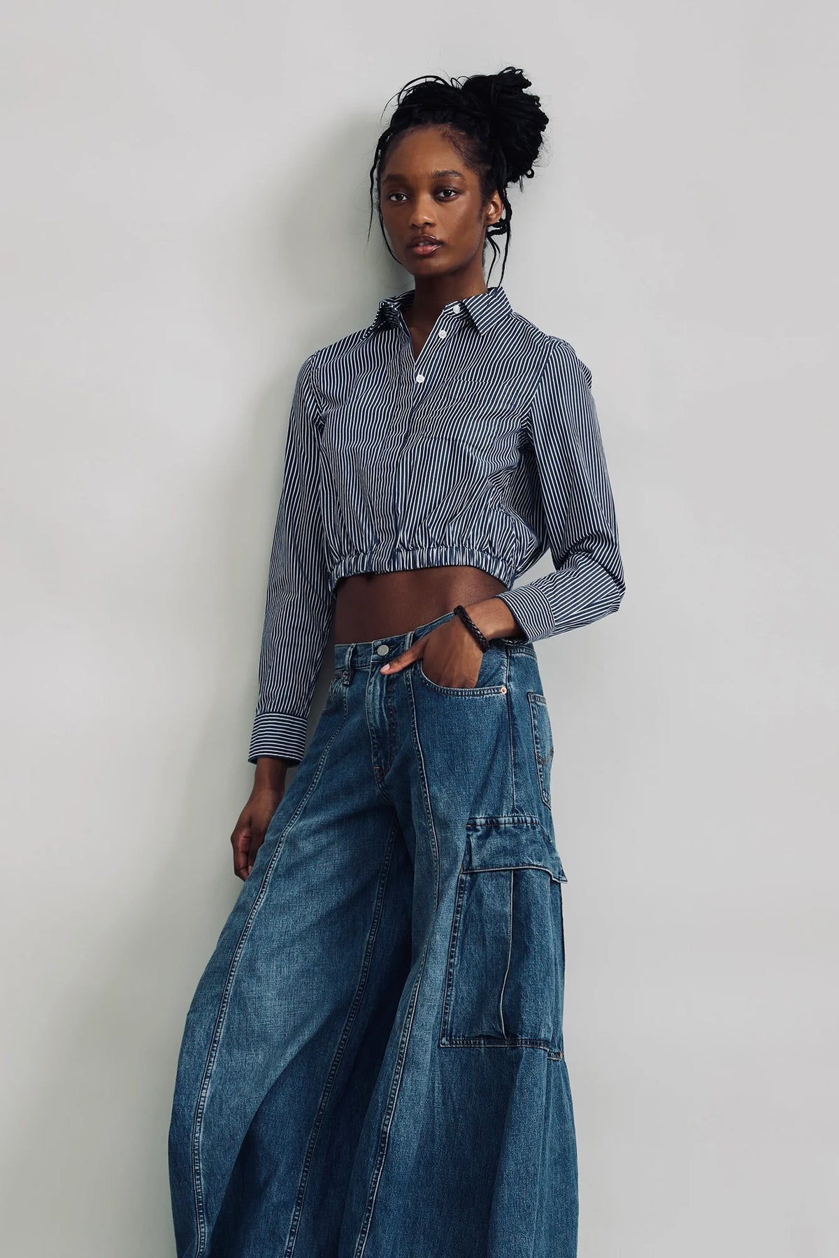 Cropped elastic waist shirt and wide-leg cargo jeans by Denimist styled against a light gray wall.