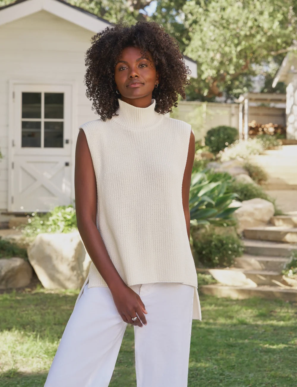 Frank & Eileen Montecito Tank in white styled with white pants, worn outdoors in a sunny garden setting.