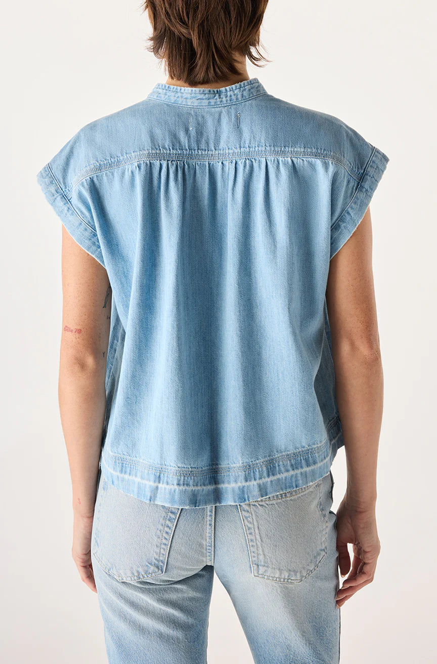 A person with short brown hair is seen from the back wearing the AMO Denim Tessa Top, a relaxed fit, light blue, 100% cotton denim short-sleeve shirt paired with matching jeans against a plain light background.