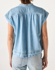 A person with short brown hair is seen from the back wearing the AMO Denim Tessa Top, a relaxed fit, light blue, 100% cotton denim short-sleeve shirt paired with matching jeans against a plain light background.