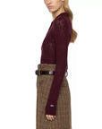Maroon argyle polo sweater by Sea New York styled with a brown high-waisted skirt, shown in profile.
