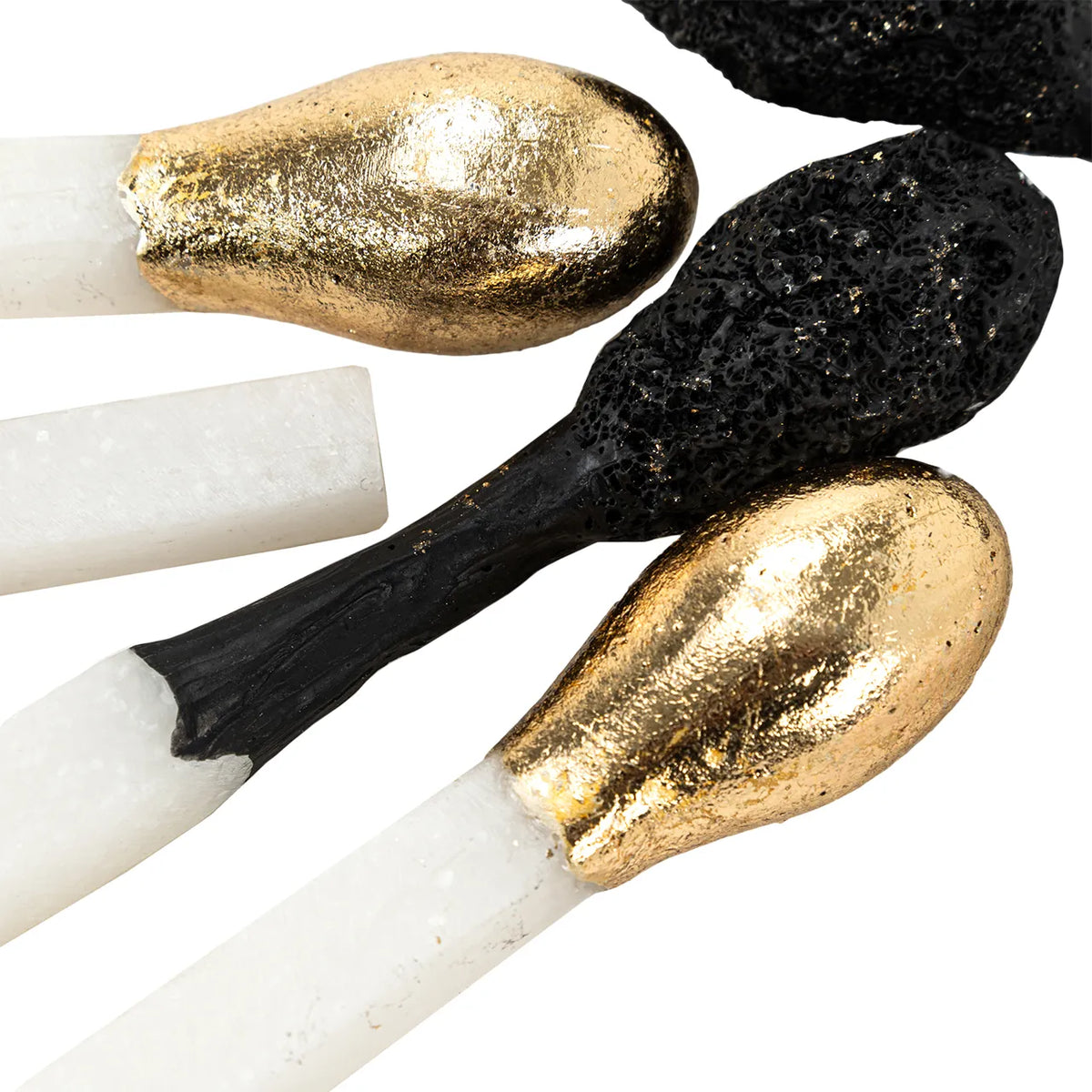 Oversized matchstick sculpture with metallic gold, matte black, and textured black heads by Bungalow Furniture.