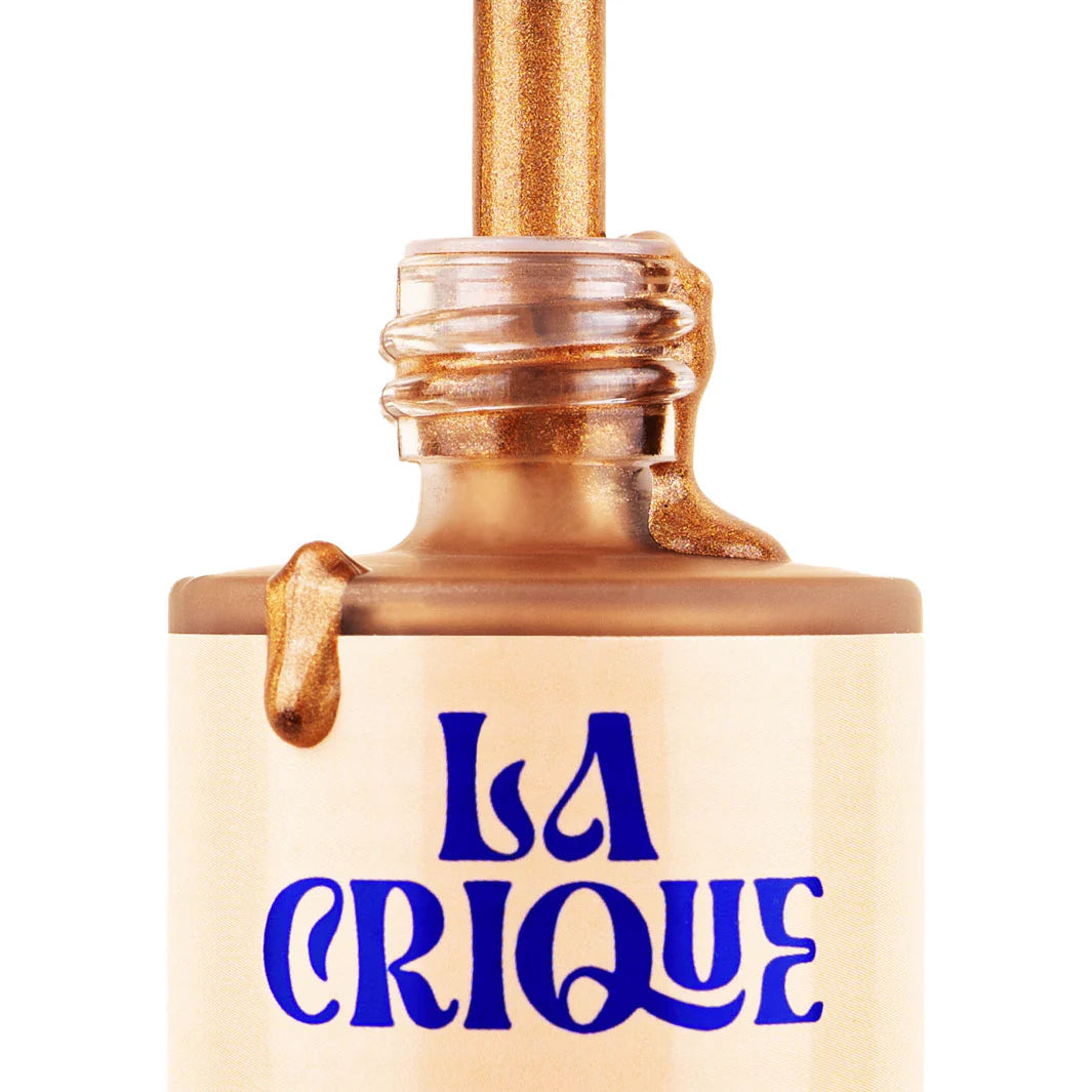 A bottle of Faire Natural Bronzing Serum Sun Radiance, with metallic gold liquid pouring from the open neck and bold blue lettering, delivers a natural glow for luminous, sun-kissed skin.