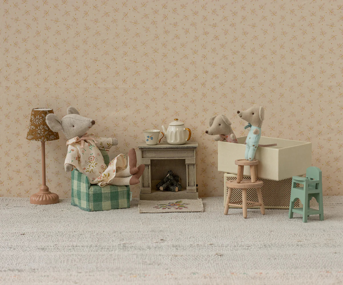 Maileg Twins, Baby mice in matchbox join another Maileg mouse in a plaid armchair inside a cozy dollhouse room, complete with a lamp, teapot, fireplace, and charming miniature furniture for a homey scene.