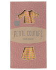 The Maileg Mum Suit by Maileg comes in a pink cardboard package with cutouts showcasing a patterned blouse, skirt, and stylish lady bag—charming clothes designed especially for your toy mouse.