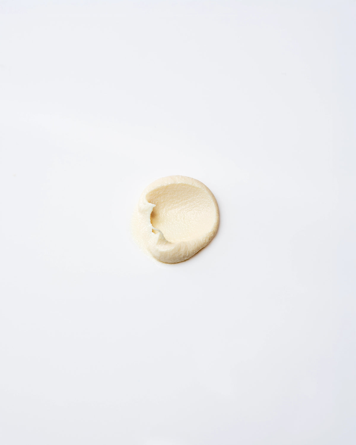 A small dollop of Faire Tallow Sunscreen SPF 50 is spread in an oval shape on a smooth, white surface.