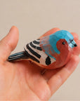 Blue hand-painted carved wood bird with rustic red, black, and white details by Faire.