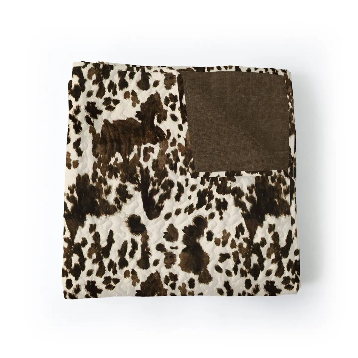 The Faire Bella Hide Brown Quilt features a folded design with a brown and white cowhide pattern and a solid brown corner patch, blending contemporary style with Texas-inspired charm for any space.