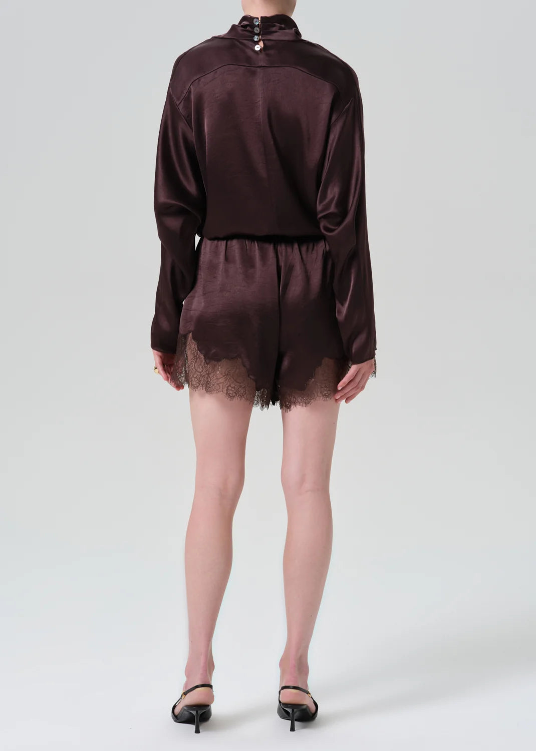Lace trimmed tap shorts and dark satin top by Citizens Of Humanity AGOLDE, model back facing in black heels.