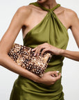 Staud Muse Clutch in brown speckled haircalf, held by woman in a green halter top against plain background.