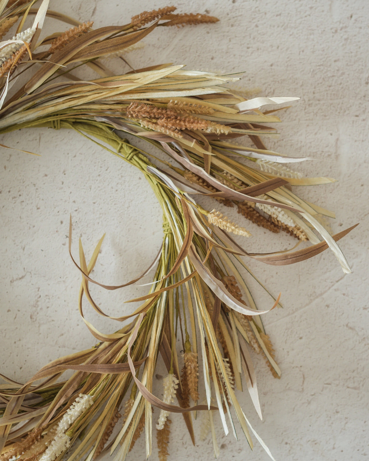 Square wreath with dried grasses in desert heather by Faire, displayed on a light textured background.