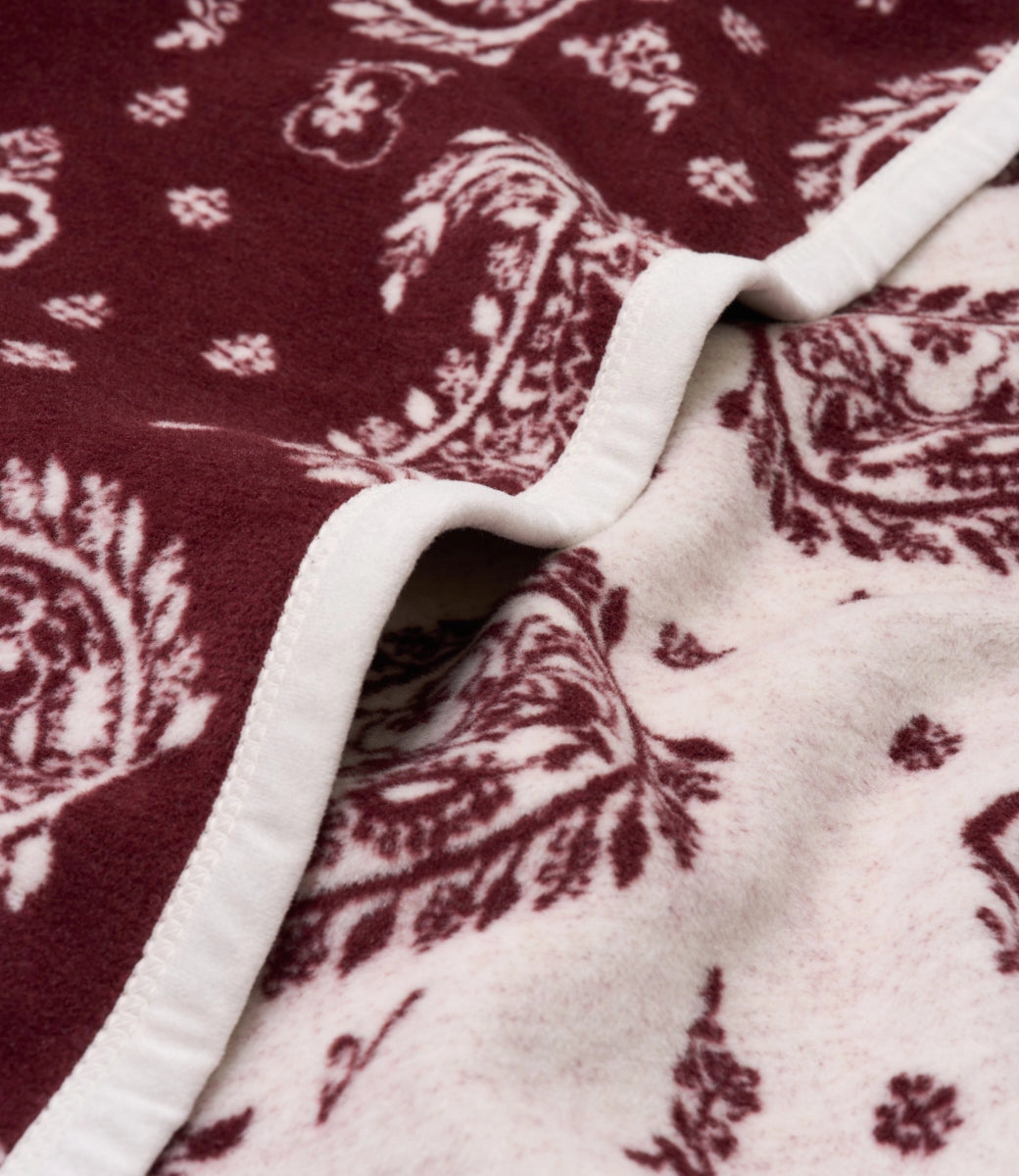 Faire Palmer Paisley Blanket with maroon and white paisley pattern, finished with a white trim.