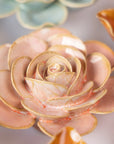 Close-up of Faire's Peach Pink Cloni Ranunculus, featuring ceramic flowers with pink and peach-toned petals, a glossy finish, and intricate detailing, set against a blurred pastel background.