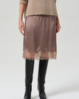 Lace-trimmed skirt from Citizens Of Humanity/AGOLDE paired with tan sweater and black knee-high boots.