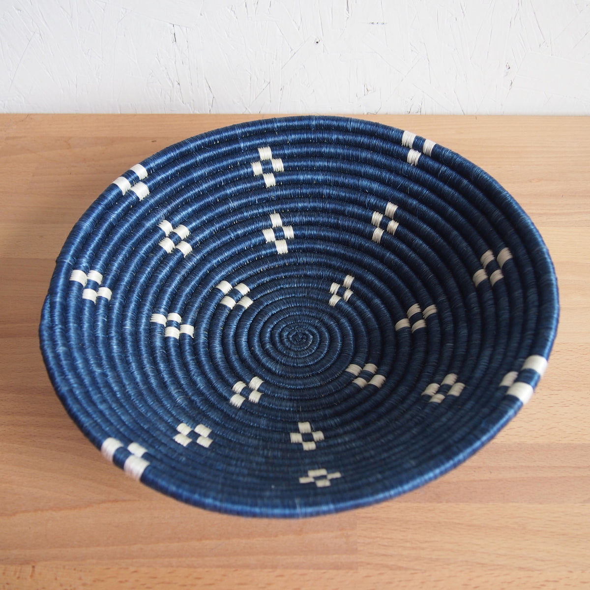 Round blue bowl with white patterns by Faire, displayed on a light wood surface for Bungalow Furniture & Accessories.