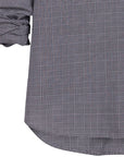 A close-up of a person wearing the Oona Continuous Button-Up Shirt by Frank & Eileen, a relaxed fit, black and white checkered long-sleeve 100% cotton shirt with rolled-up sleeves. Only the torso and arms are visible.