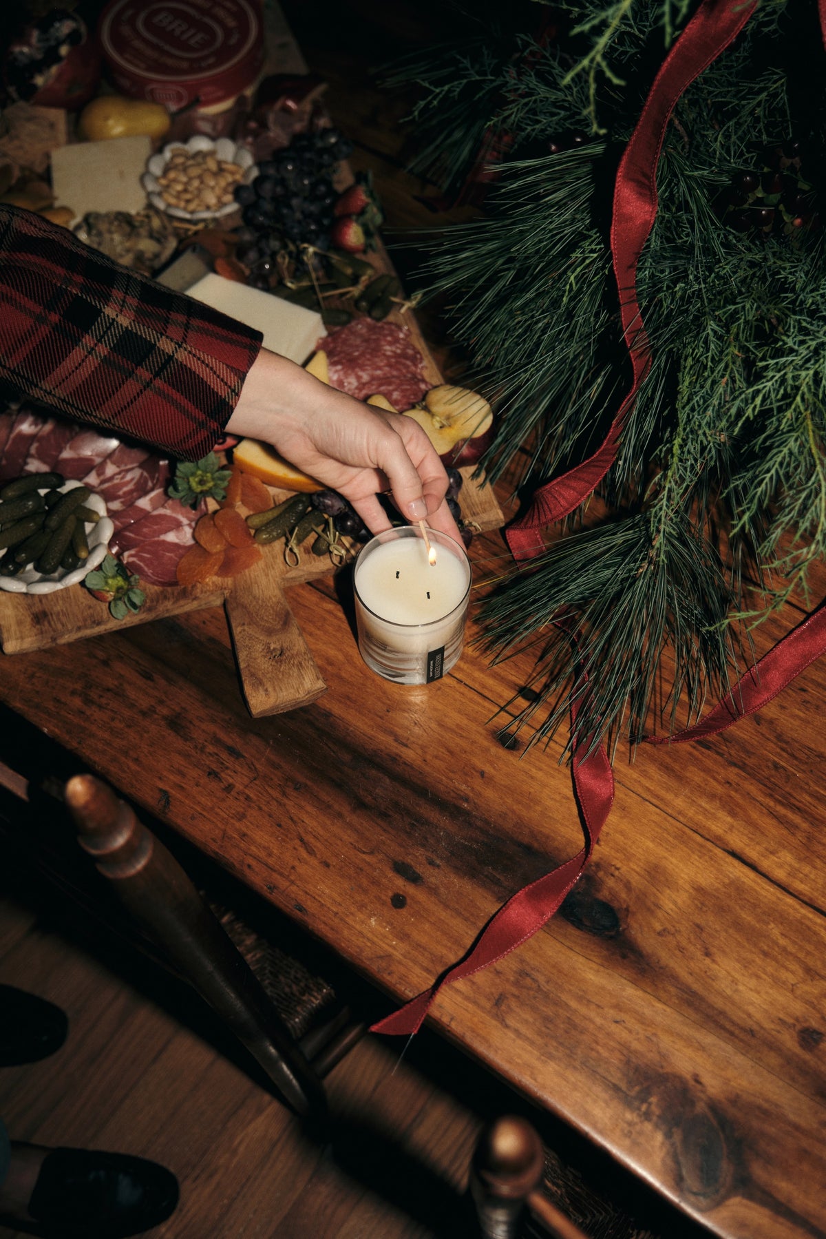 Cowboy Christmas candle being lit on a rustic wooden table in a festive, cozy holiday setting.