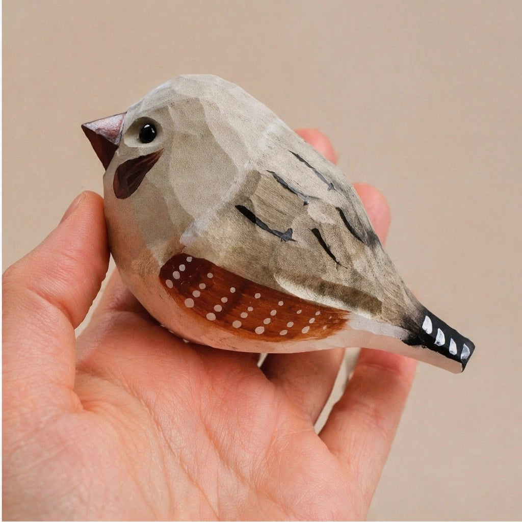 Gray hand-painted carved wood bird figurine by Faire, crafted from basswood, shown in hand for scale.